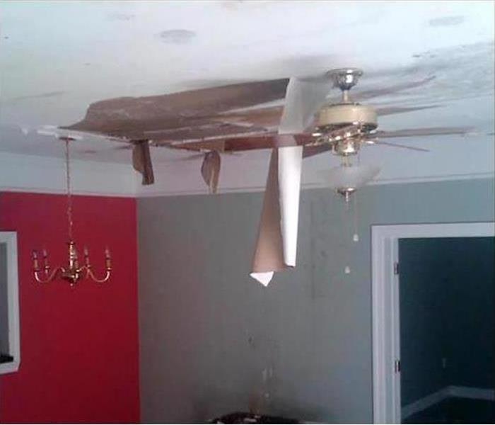 water damaged ceiling in home with drywall hanging down into room